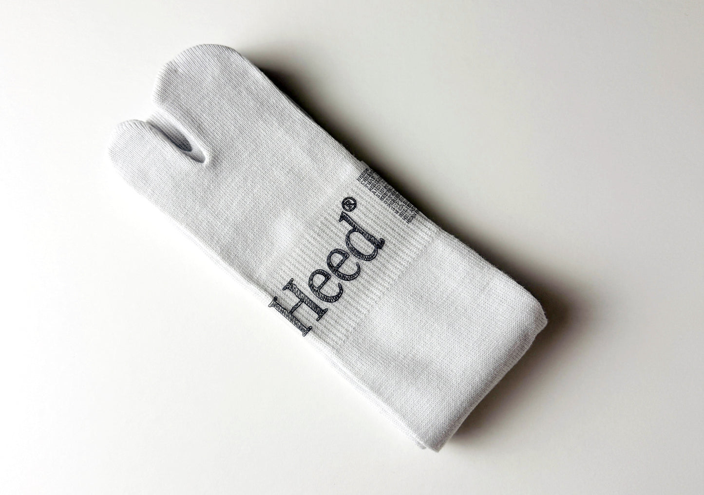 Heed Traditional Jika Tabi Toe Socks - Cotton Breathable Arch Support Socks (White):  Flat-lay image of the Heed white cotton Jika Tabi toe socks. The socks feature the iconic split-toe design and a tube sock silhouette for a secure, comfortable fit. The reinforced arch support and breathable cotton material are also visible in the image. From your Mental Health and Self Care Streetwear Clothing Brand.